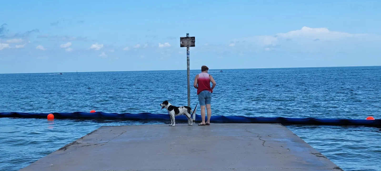 A pier over blue water with people fishing at the end