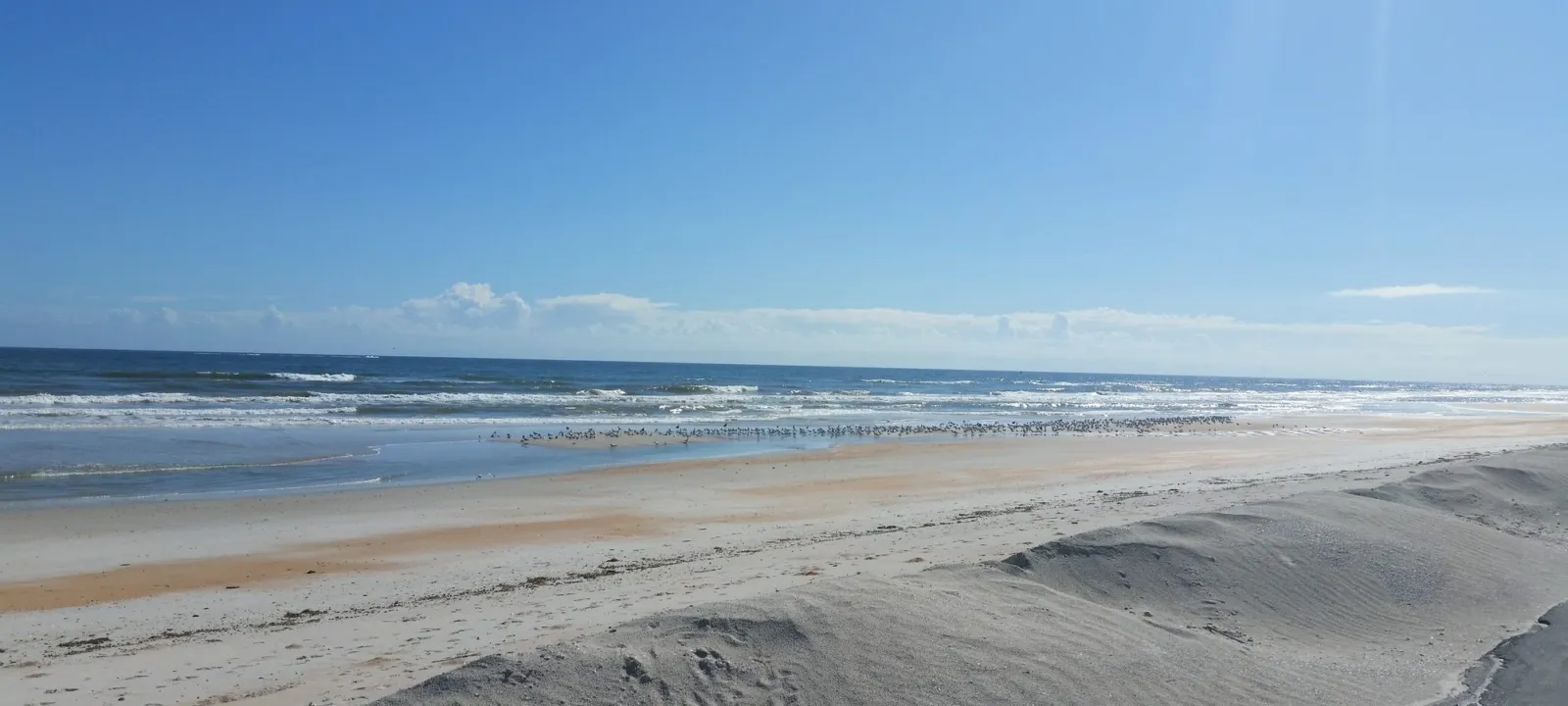A wide beach meeting blue water