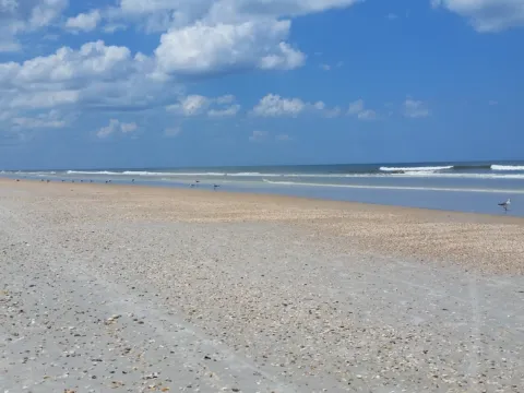 A wide, empty Florida beach under a blue sky