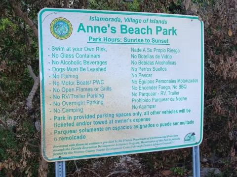 The Islamorada village sign at Anne’s Beach Park listing park rules, including Dogs Must Be Leashed and hours of sunrise to sunset.