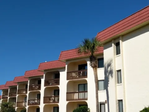 Balconies of a beachfront condo building with a palm