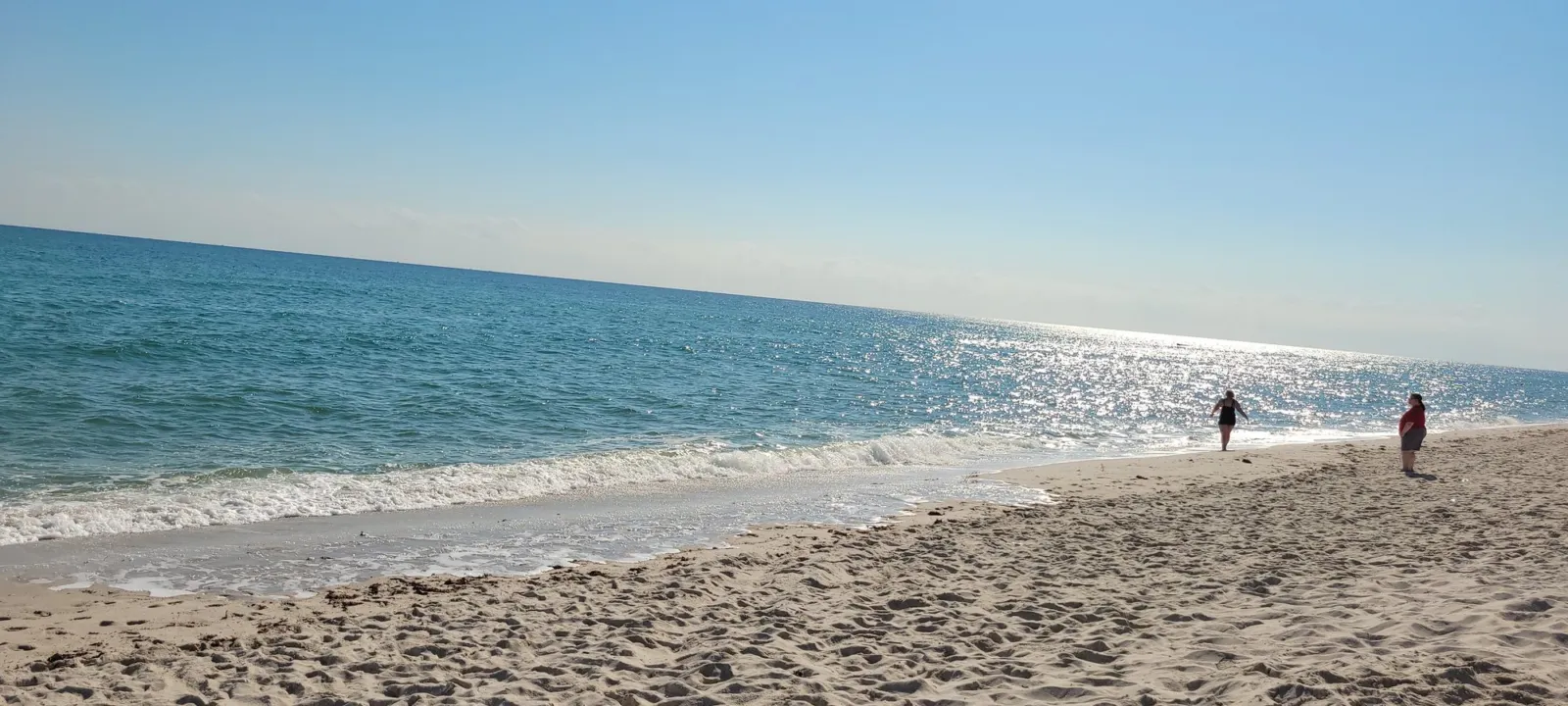 Calm, shallow water along a white sand beach