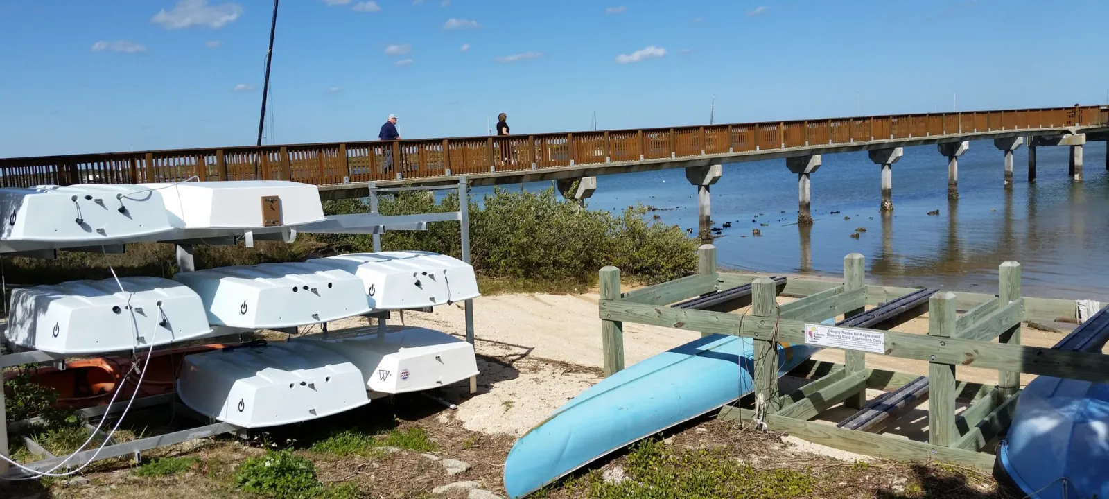 Kayaks and canoes pulled up on a sandy shore near the water.