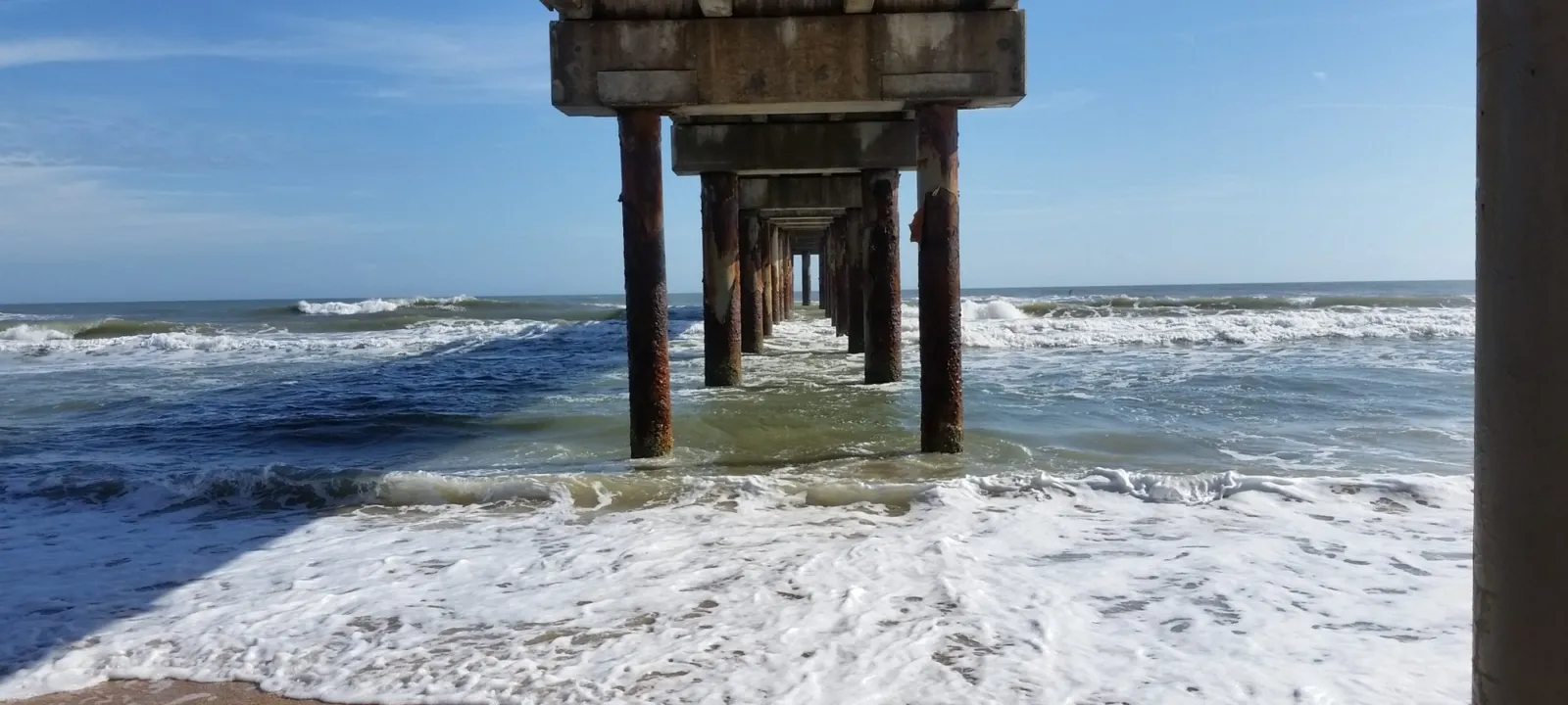 Looking out to the surf from beneath a fishing pier