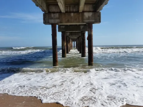 Looking out to the surf from beneath a fishing pier
