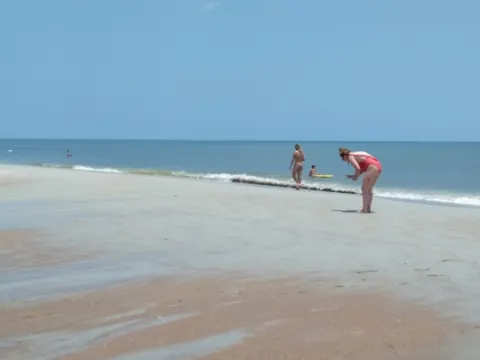 People and cars on a wide, hard-packed beach