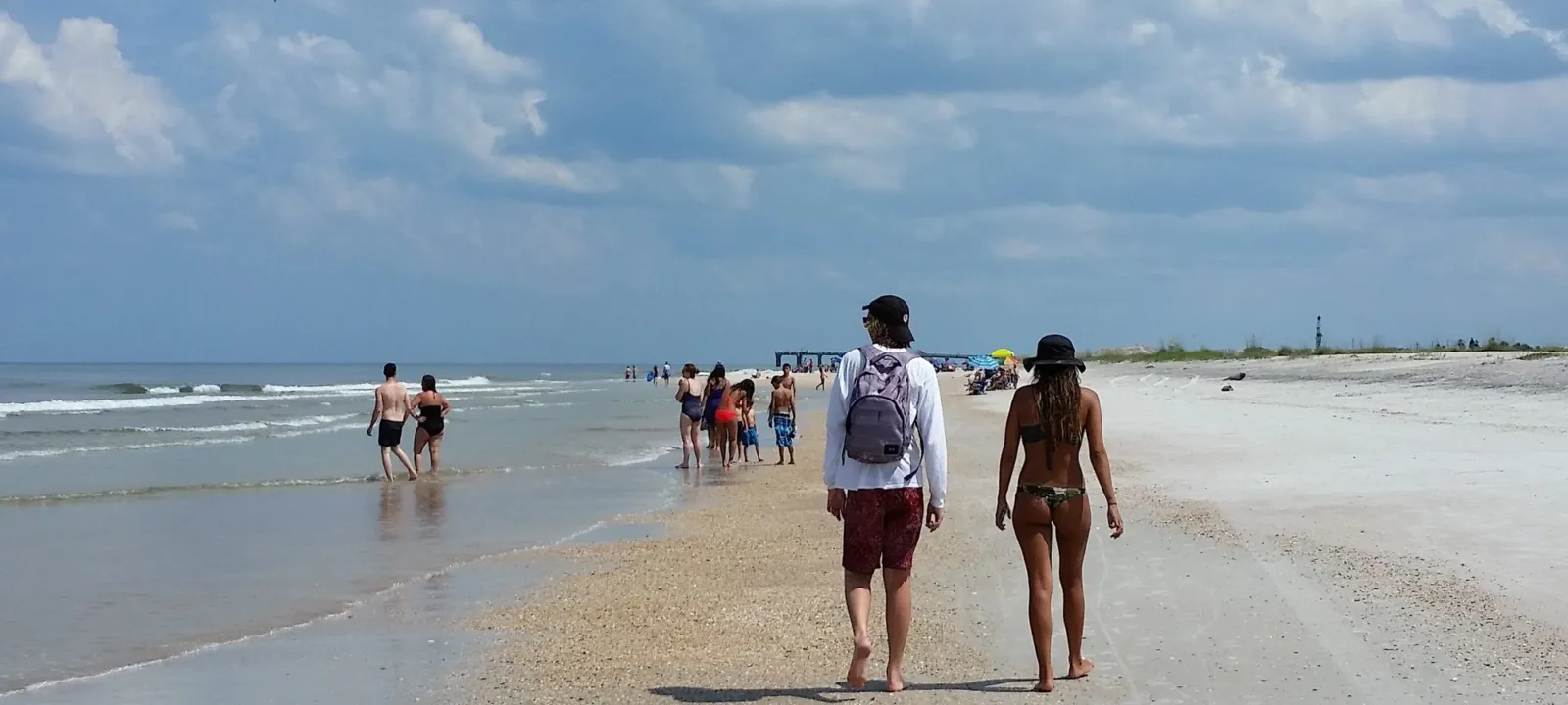 People walking along the water line on a sunny beach