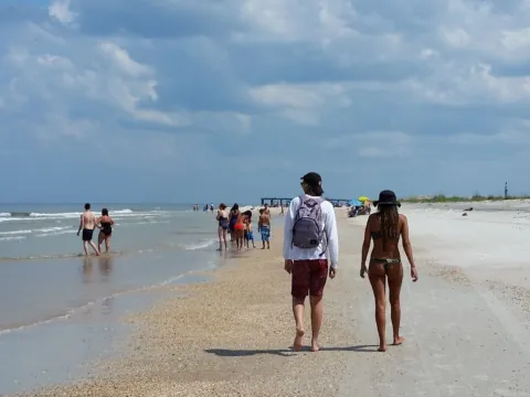 People walking along the water line on a sunny beach