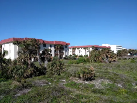 Resort buildings behind coastal scrub