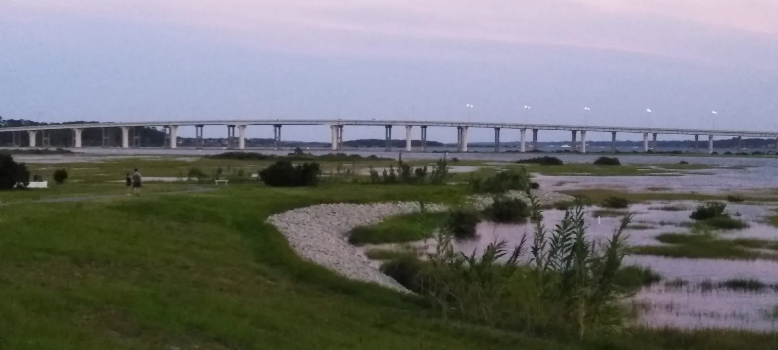A salt marsh at dusk, its pools reflecting a pink evening sky.