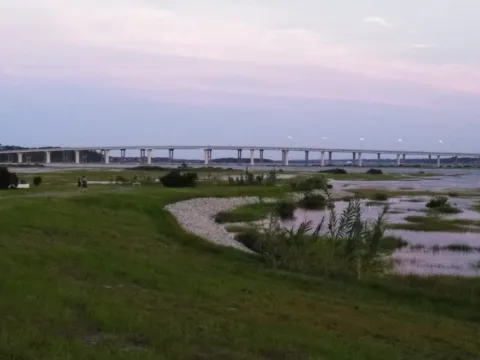 A salt marsh at dusk, its pools reflecting a pink evening sky.