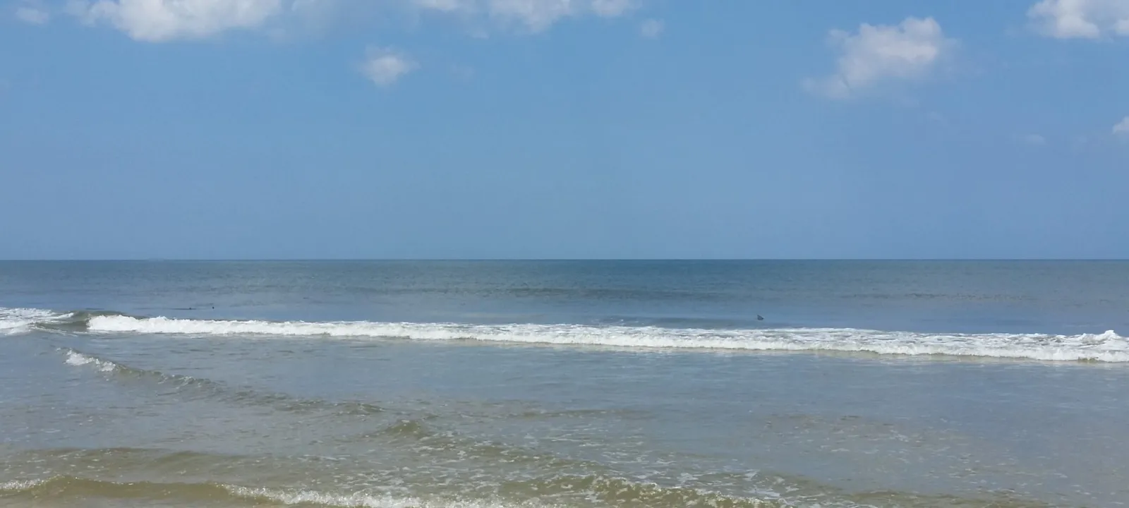 Small waves running up a wide beach.