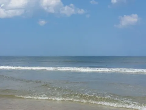 Small waves running up a wide beach.
