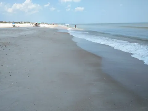 Waves washing up a wide, empty beach